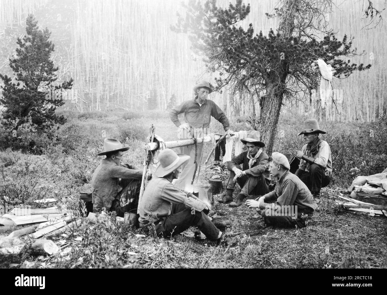 Kanada: ca. 1922 Cowboys sitzen am Lagerfeuer und warten darauf, dass ihr Abendessen kocht. Stockfoto