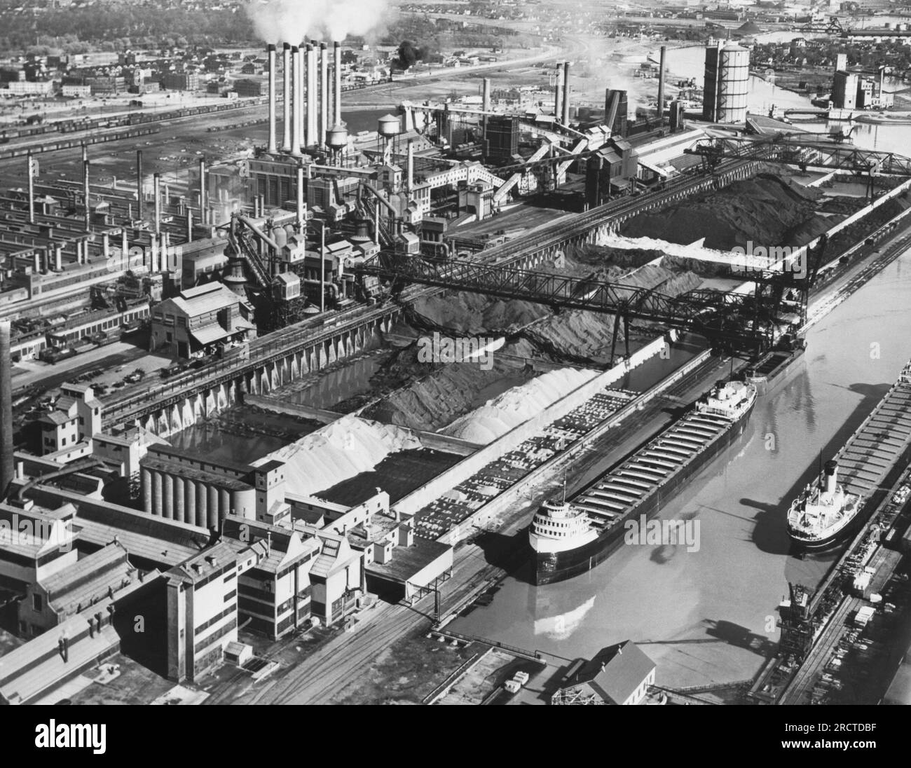 Dearborn, Michigan: Mai 1947, Werk River Rouge der Ford Motor Company, in dem im Hintergrund Eisenerz, Kohle und Kalkstein zur Versorgung der Hochöfen, der Gießerei und des Kraftwerks gelagert werden. Zwei Eisenerzträger befinden sich am Dock rechts. Stockfoto