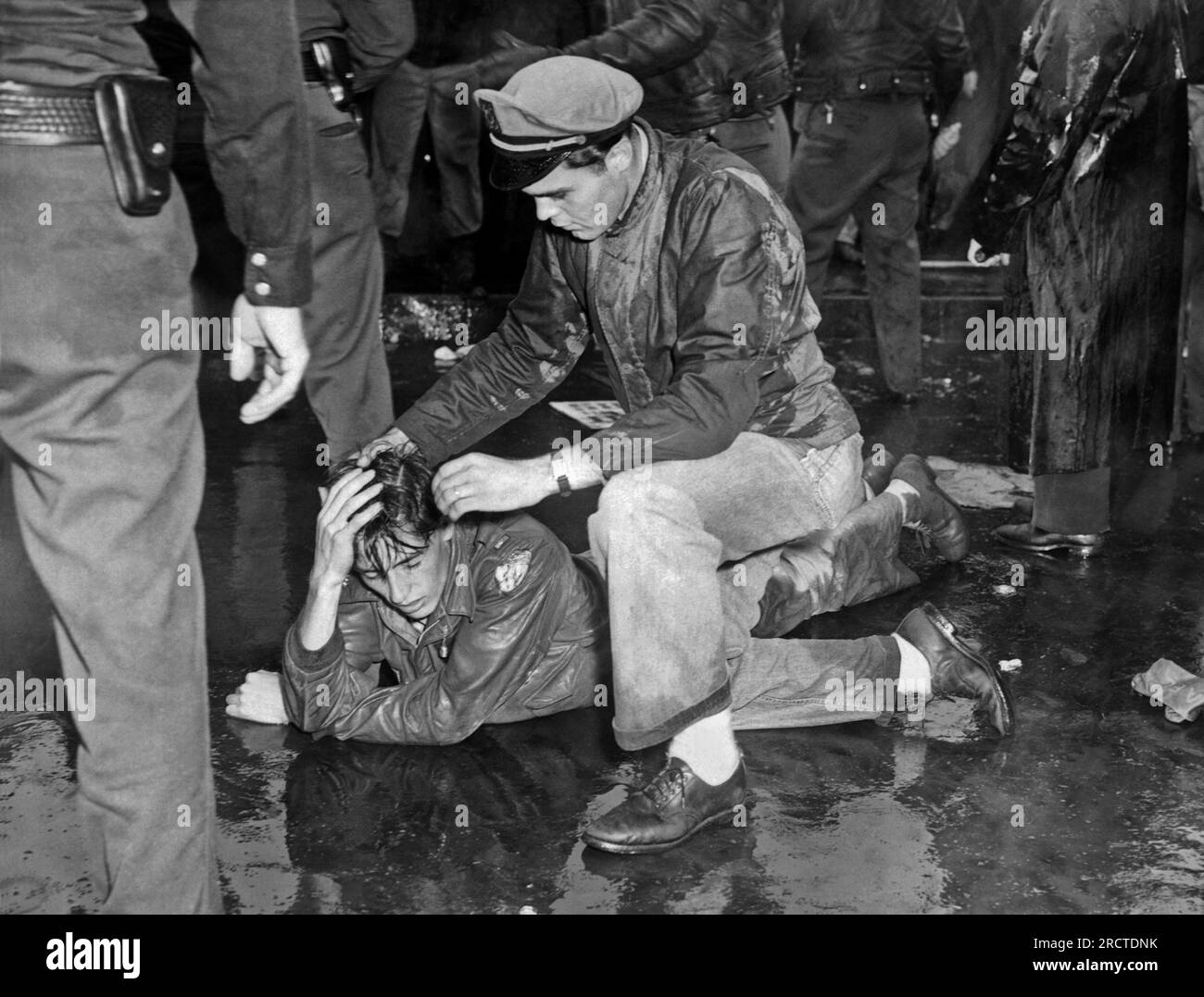 Los Angeles, Kalifornien: 1. Oktober 1946. Ein ververletzter Demonstrante in den MGM Studios liegt auf dem Bürgersteig, während ein Genosse versucht, ihm nach der Schlacht mit der Polizei und den Hilfssheriffs zu helfen. Viele der Parader sind Kriegsveteranen, die während des Streiks ausgesperrt wurden. Stockfoto