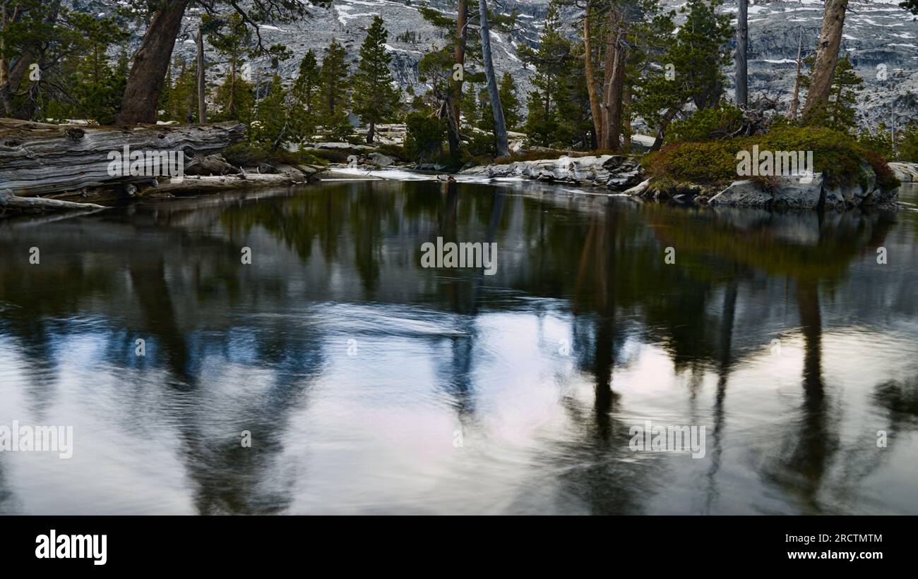 Himmel und Bäume spiegeln sich im ruhigen See. Stockfoto