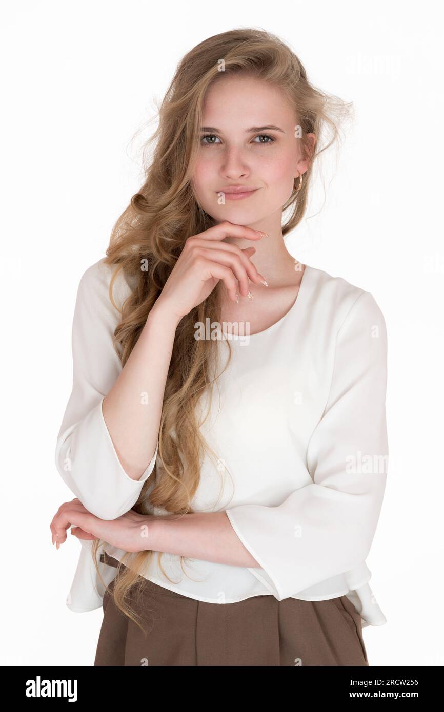 Porträt einer Weißen jungen Frau von 21 Jahren, die in die Kamera schaut. Wunderschöne blonde Frau mit langen Haaren, gekleidet in weißer Bluse und brauner Hose Stockfoto