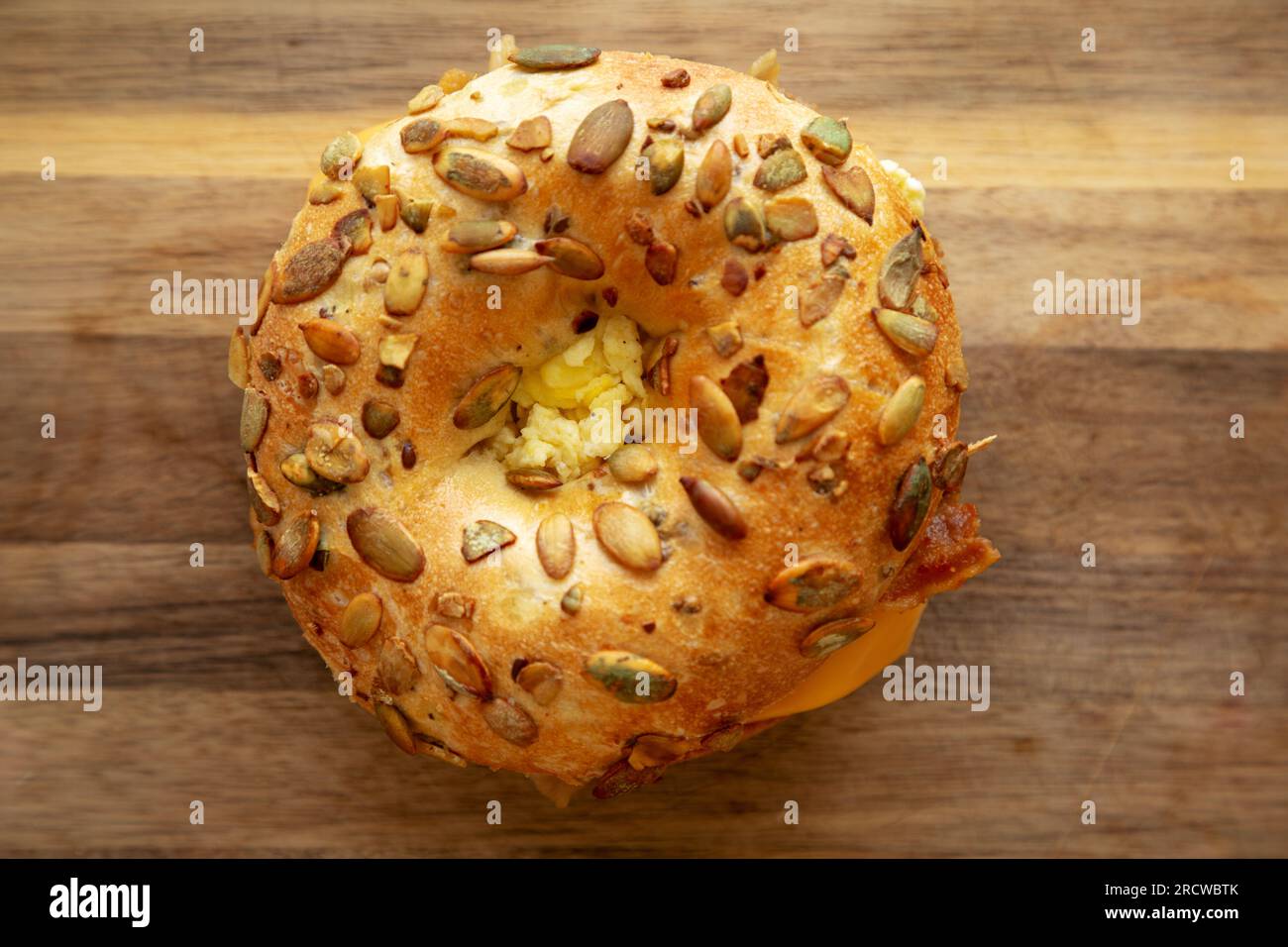 Hausgemachtes Bacon, Ei & Cheese Bagel Frühstückssandwich auf einem Holzbrett, Blick von oben. Nahaufnahme. Stockfoto