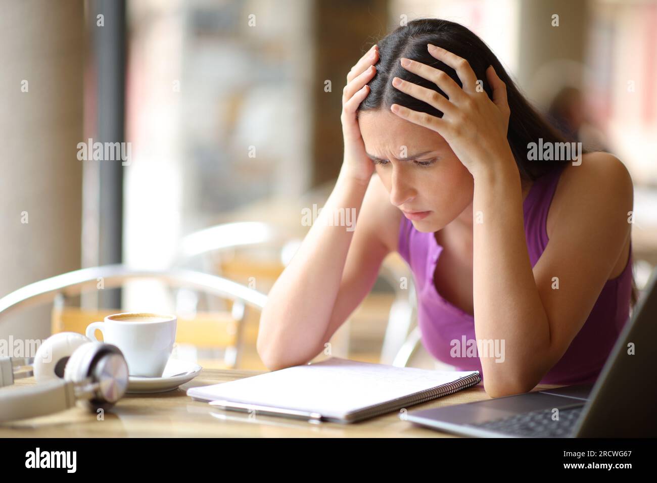Besorgte Schülerin, die versucht hat, sich eine Lektion aus dem Notizbuch auf einer Barterrasse auswendig zu lernen Stockfoto
