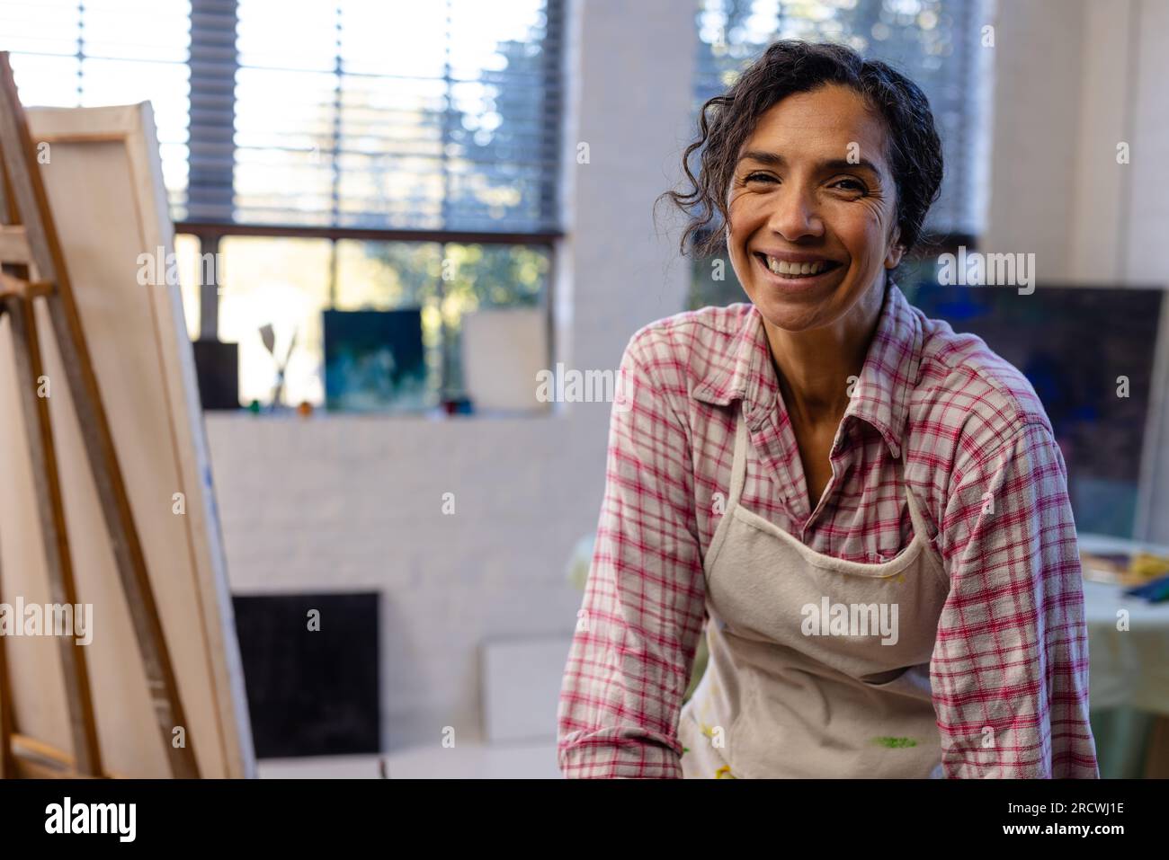 Porträt einer glücklichen, birassischen Frau, die eine Schürze im Studio trägt Stockfoto