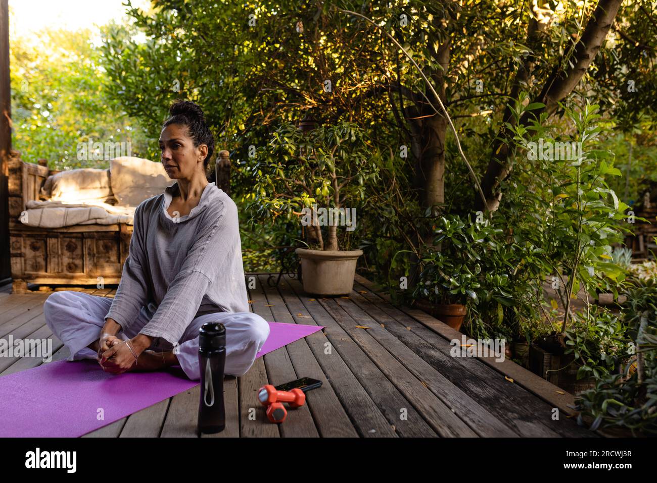 Birassische Frau, die Yoga macht, sich auf der Terrasse im Garten streckt, Kopierraum Stockfoto