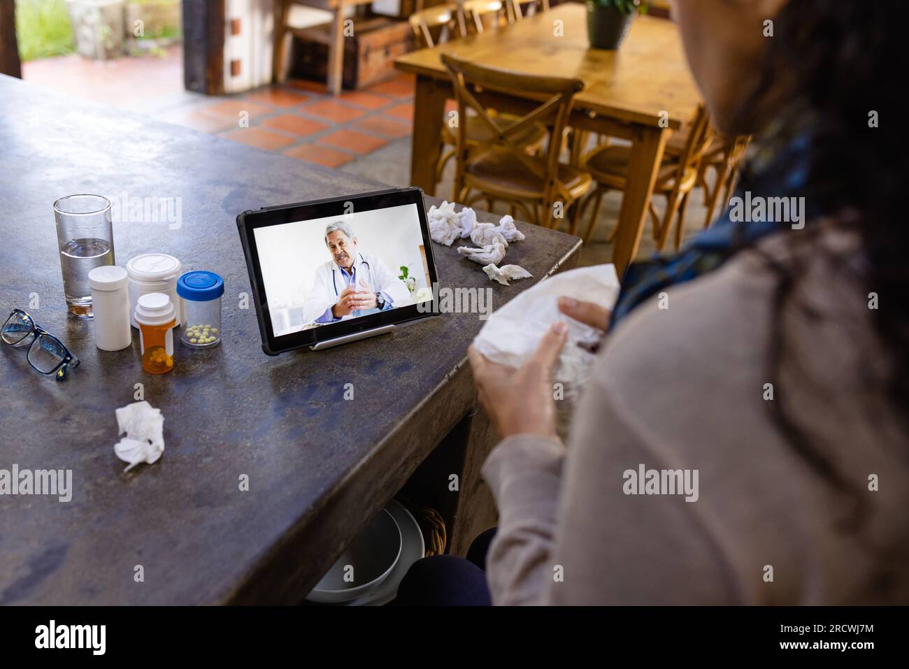 Birassische Frau, die auf der Arbeitsfläche sitzt, mit Tablette für medizinische Beratung mit birassischem Arzt Stockfoto