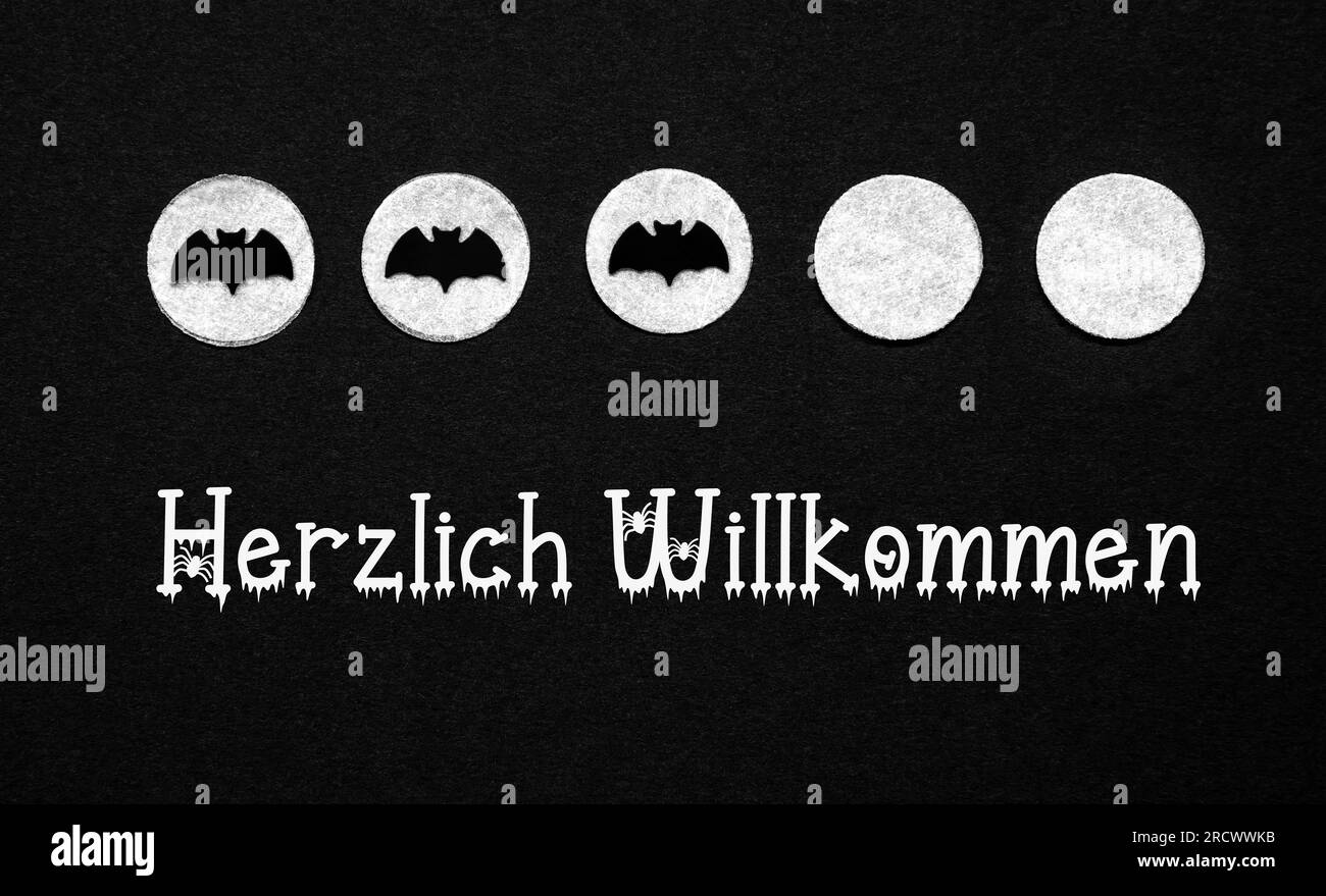 Schwarzer Halloween-Hintergrund mit weißen Punkten mit Fledermäusen und deutschem Text Herzlich Willkommen, was bedeutet Willkommen auf Englisch Stockfoto