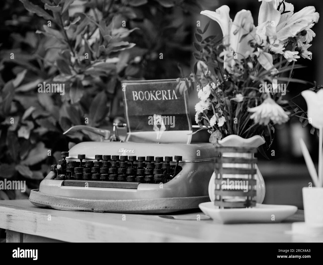 Mechanische, militärisch arbeitende Bisel-Schreibmaschine. Topf mit rosa Blumen. Restaurantwerbung für Vintage-Accessoire. Augenfänger. Requisiten, um sie anzuziehen Stockfoto