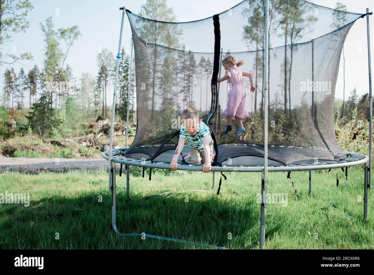 Kinder, die auf einem Trampolin in einem Garten zu Hause spielen Stockfoto