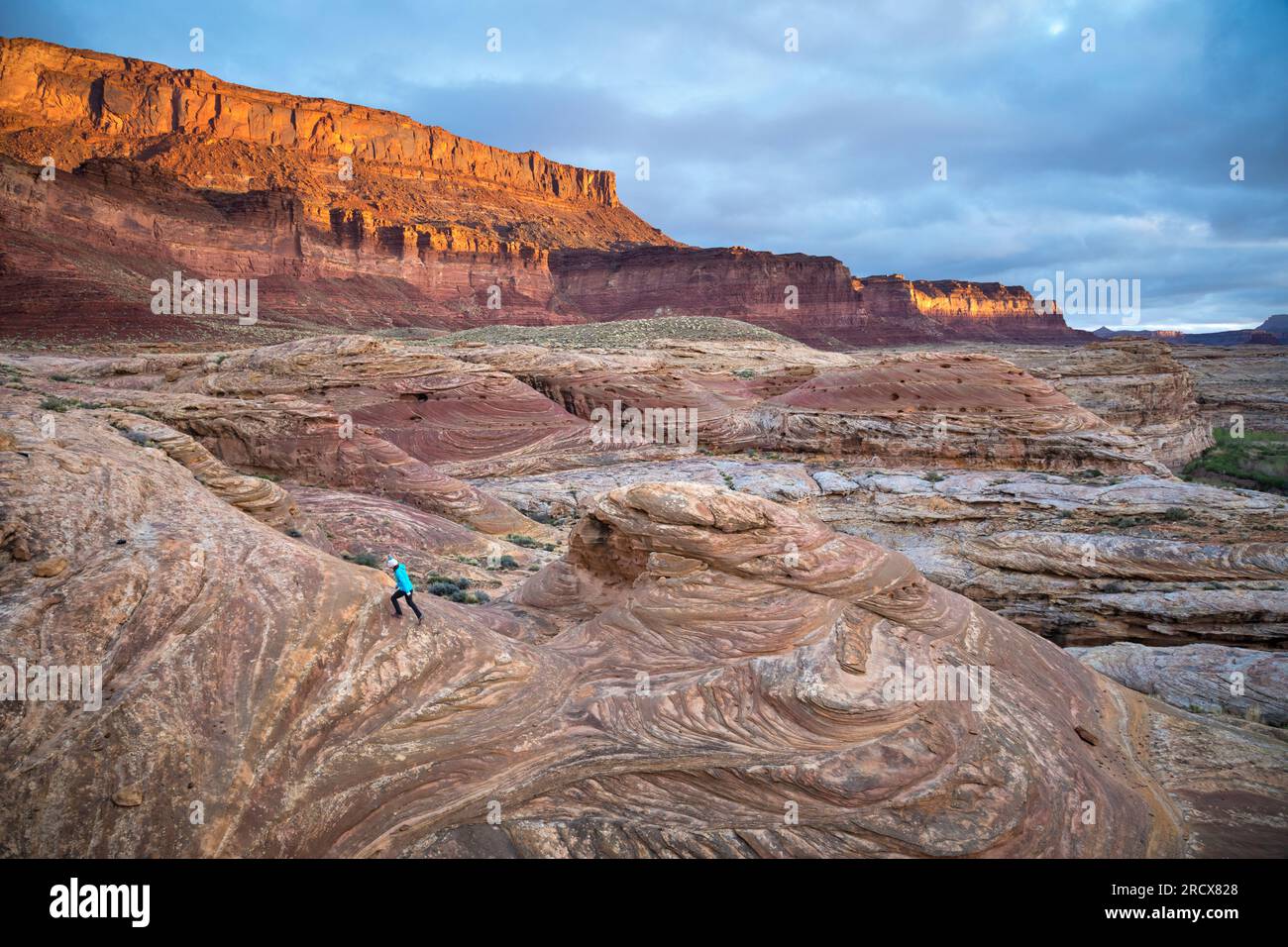 Frau wandert bei Sonnenaufgang in einer dramatischen Wüstenlandschaft. Stockfoto