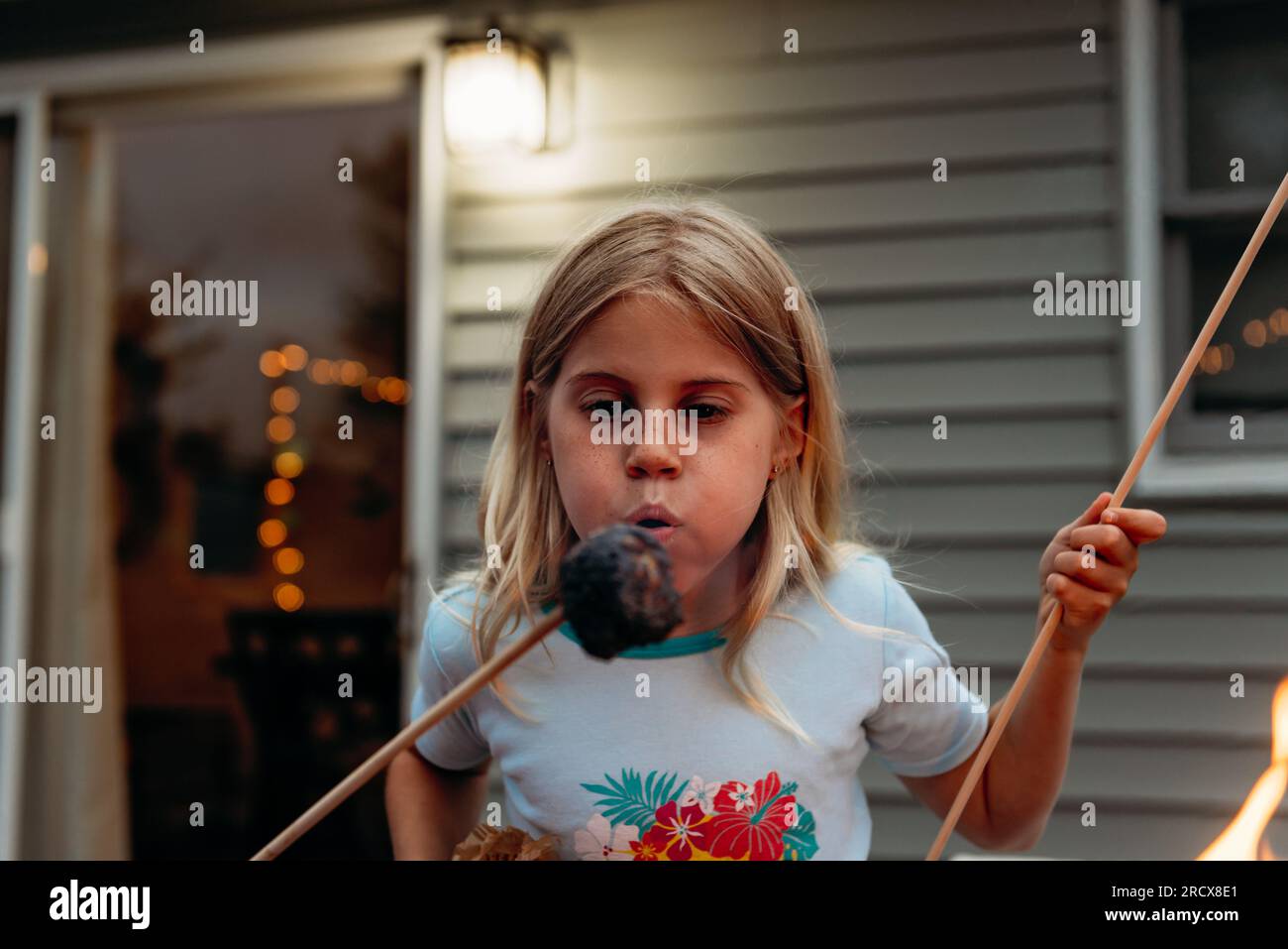 Ein Mädchen bläst Marshmallow aus, während sie S'mores macht Stockfoto