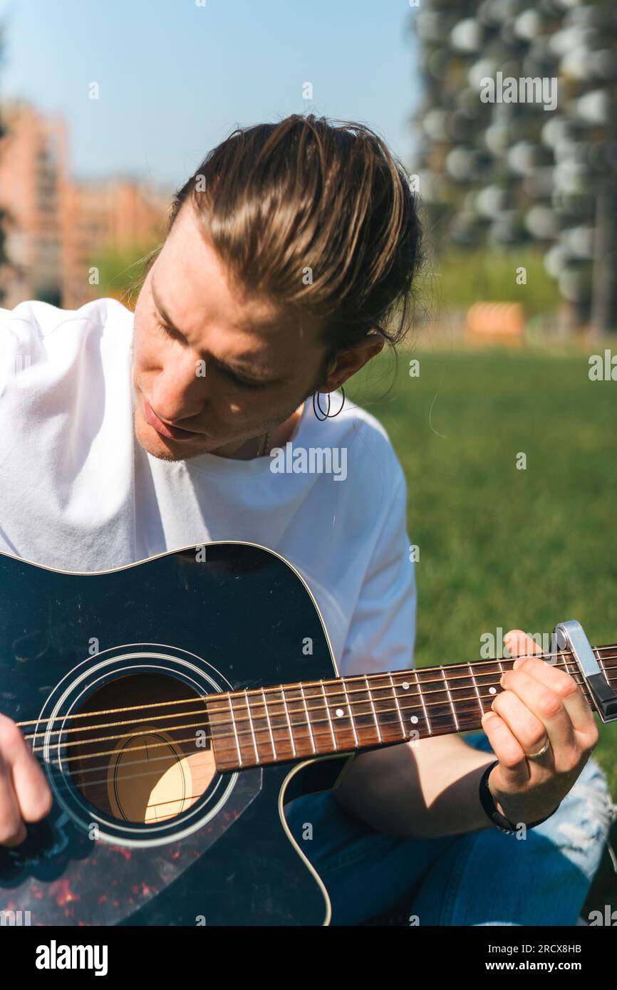 Nahaufnahme eines Sängers, der an einem sonnigen Tag in einem Garten Gitarre spielt Stockfoto