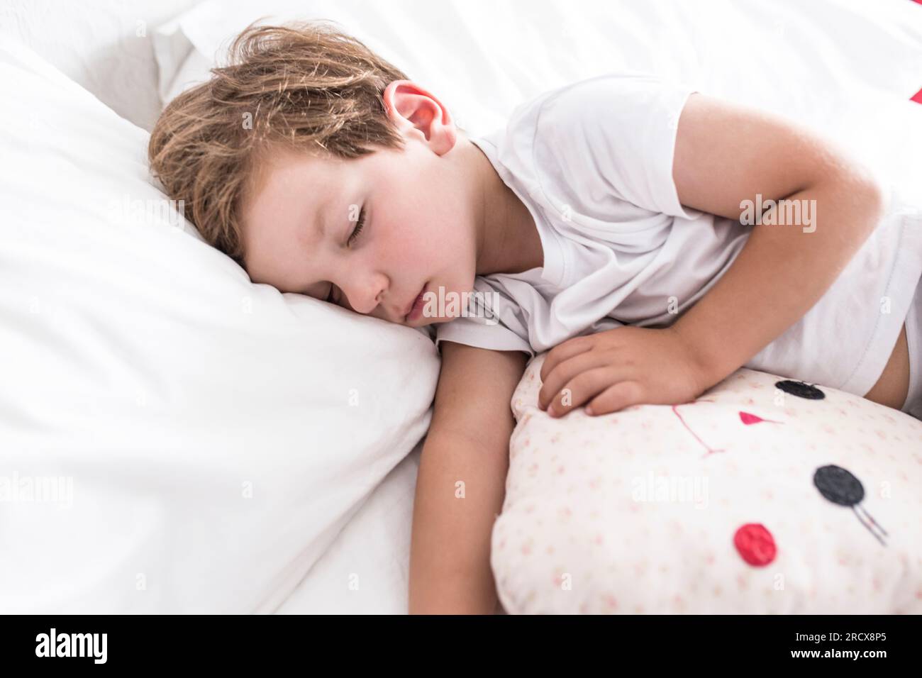 3 Jahre alter Junge, der mit seinem Lieblingskissen auf dem Bett schläft Stockfoto