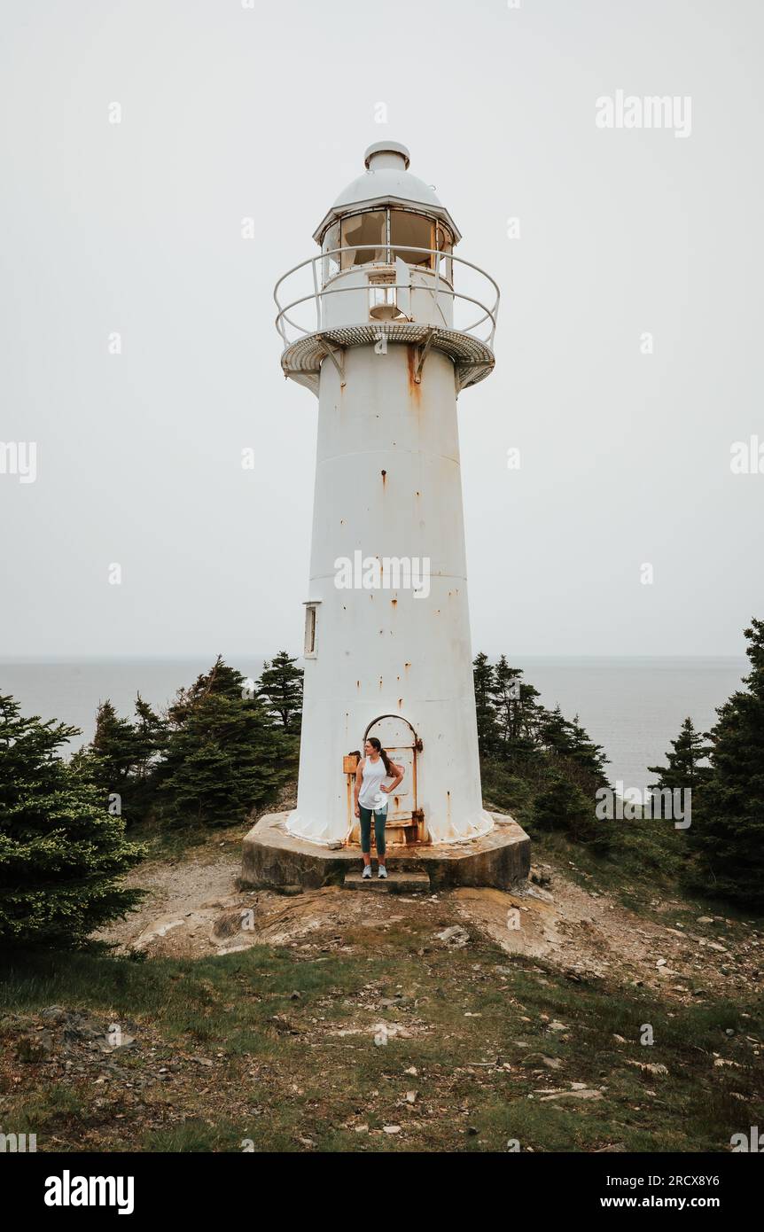 Eine Frau steht vor dem alten Leuchtturm in Neufundland, Kanada. Stockfoto