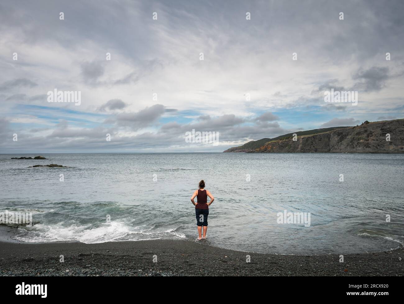 Eine Frau am Rand des Ozeans in Neufundland, Kanada. Stockfoto