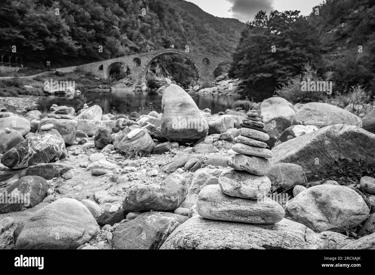 Zen kleiner Steinhaufen, flache Fokusperspektive vor der Teufelsbrücke über den Fluss Arda, Südbulgaren. Schwarzweiß-Reisefoto Stockfoto