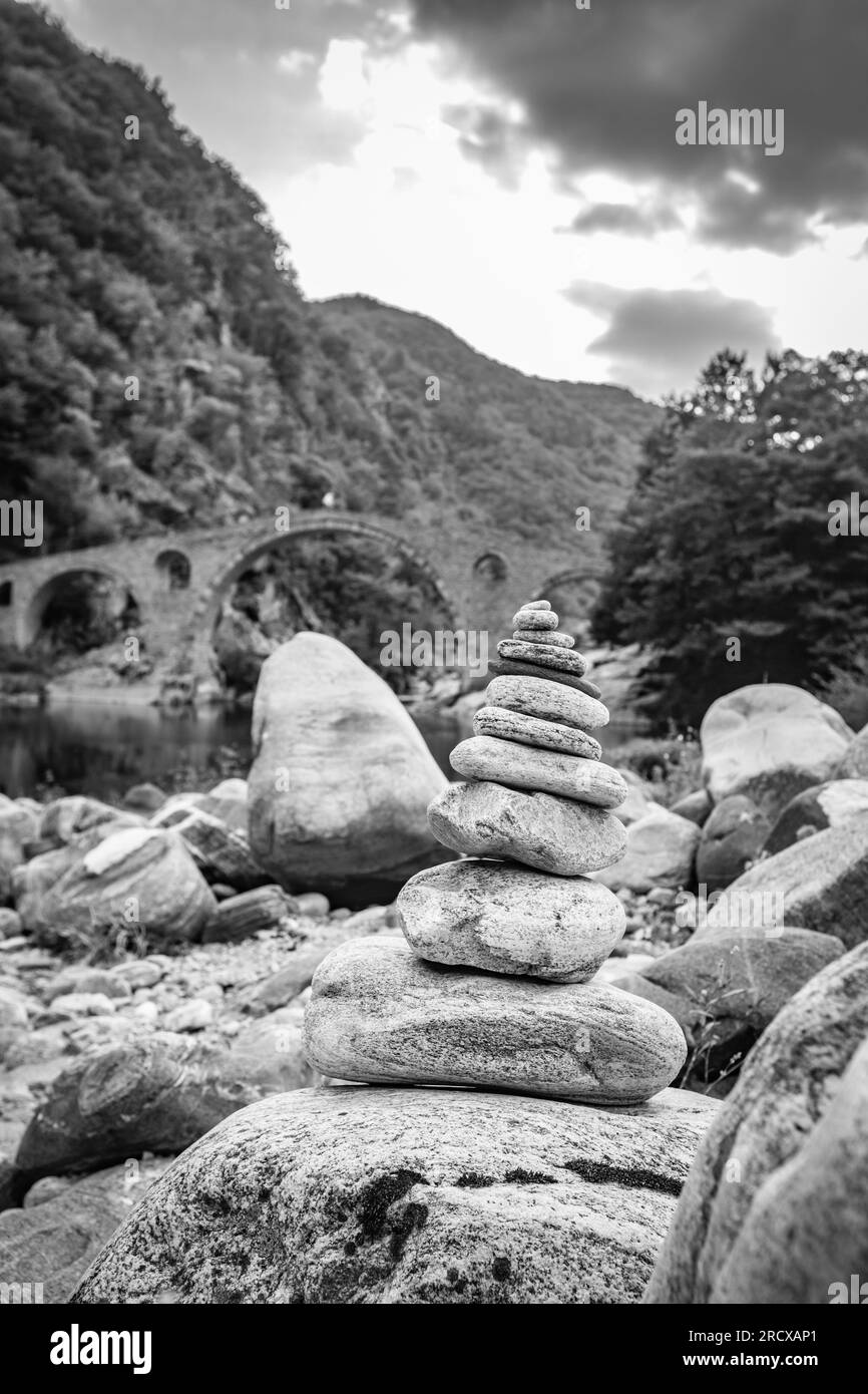Zen kleiner Steinhaufen, flache Fokusperspektive vor der Teufelsbrücke über den Fluss Arda, Südbulgaren. Schwarzweiß-Reisefoto Stockfoto