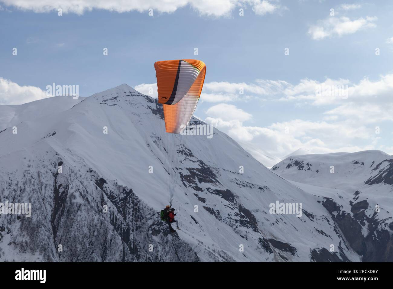 Gudauri, Georgia - 1. Mai 2019: Gleitschirme fliegen an einem sonnigen Tag vor den schneebedeckten Gipfeln des Kaukasus Stockfoto