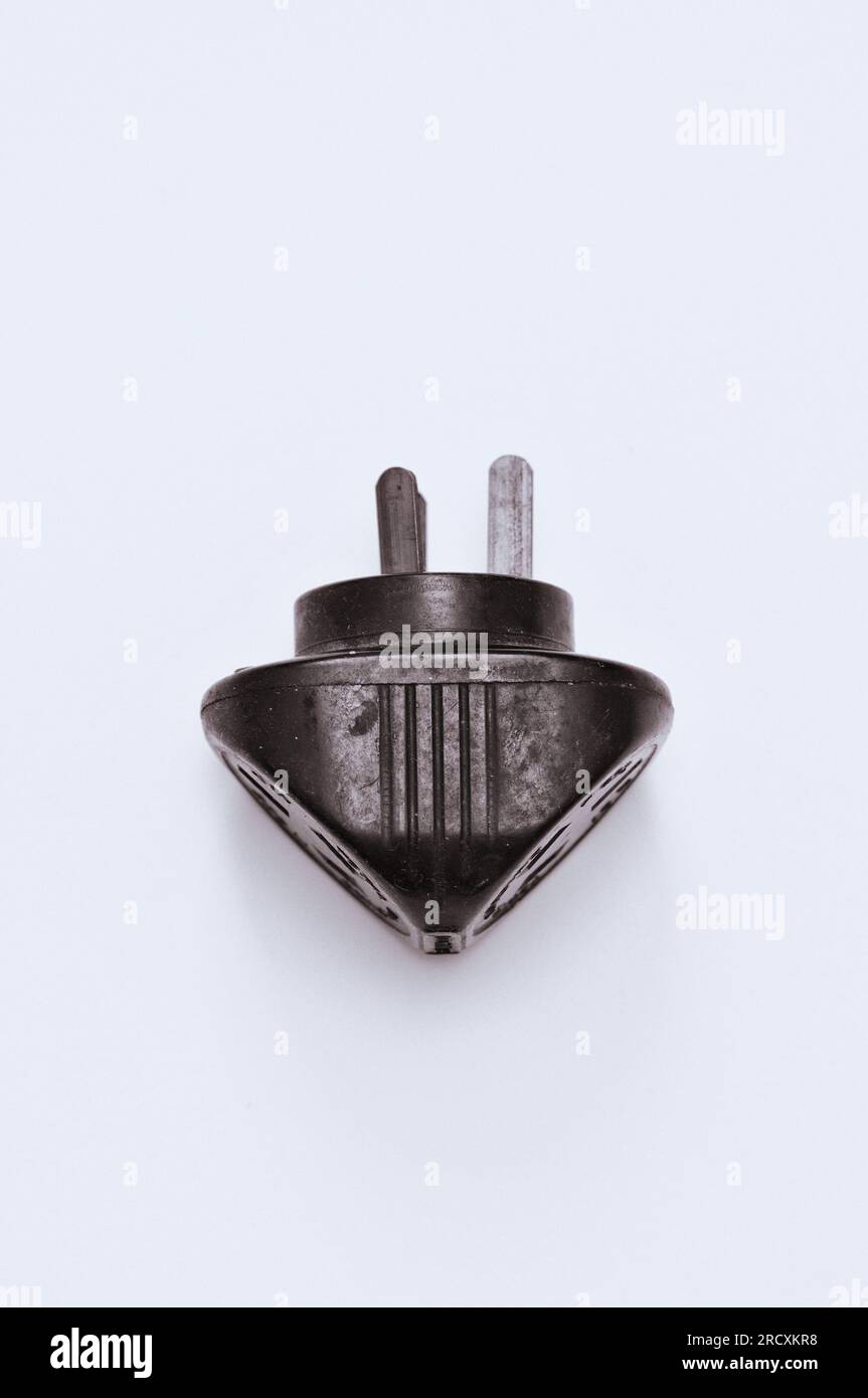 Bakelite-Doppeladapter-Stecker mit seitlicher Einprägung mit einer Reihe von Linien; Draufsicht, ein umgekehrtes Dreieck mit 3 Stiften auf weißem Papier Stockfoto