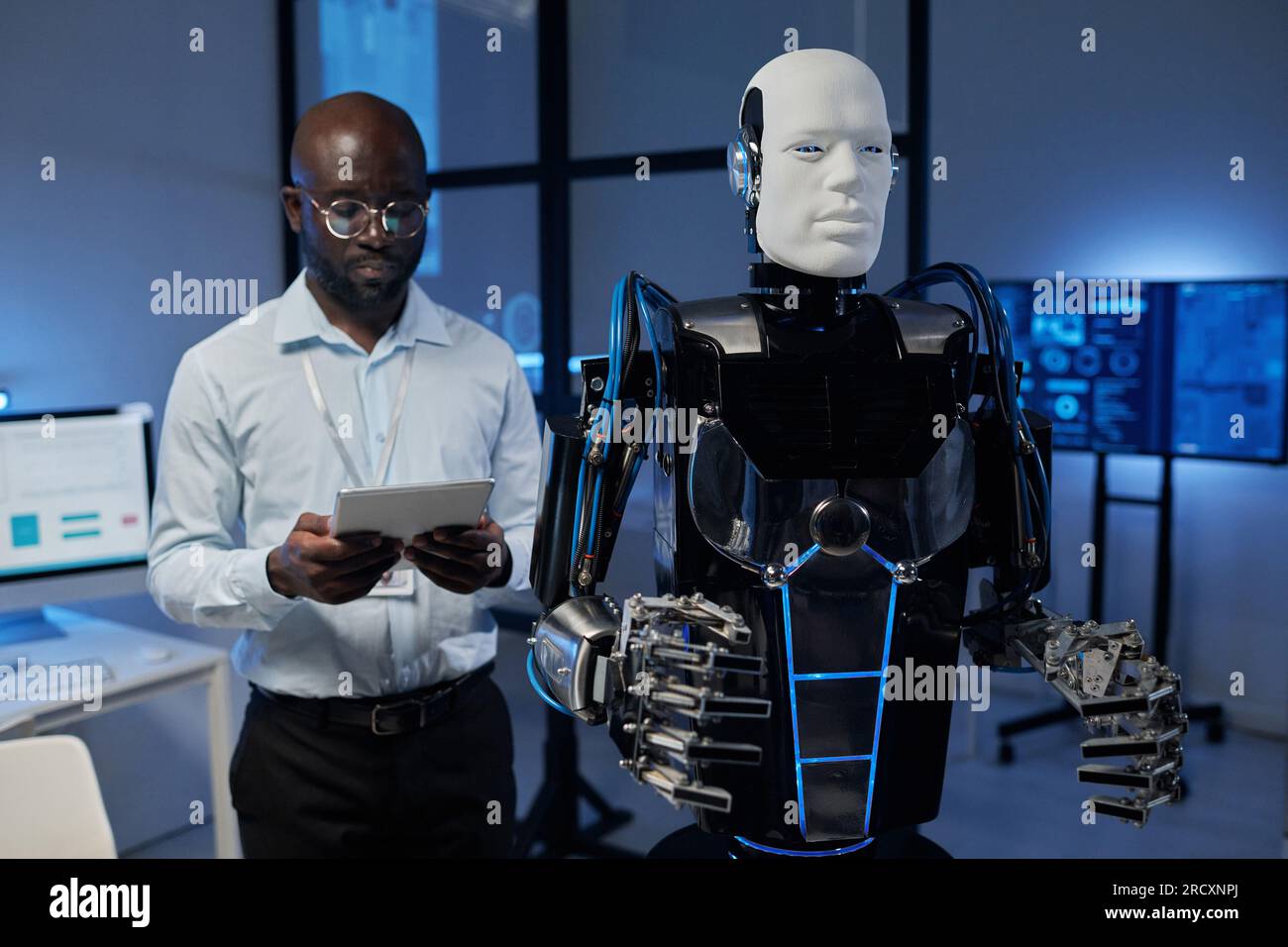 Afroamerikanischer Ingenieur, der Cyborg-Roboter mit Tablet-pc im Büro steuert Stockfoto