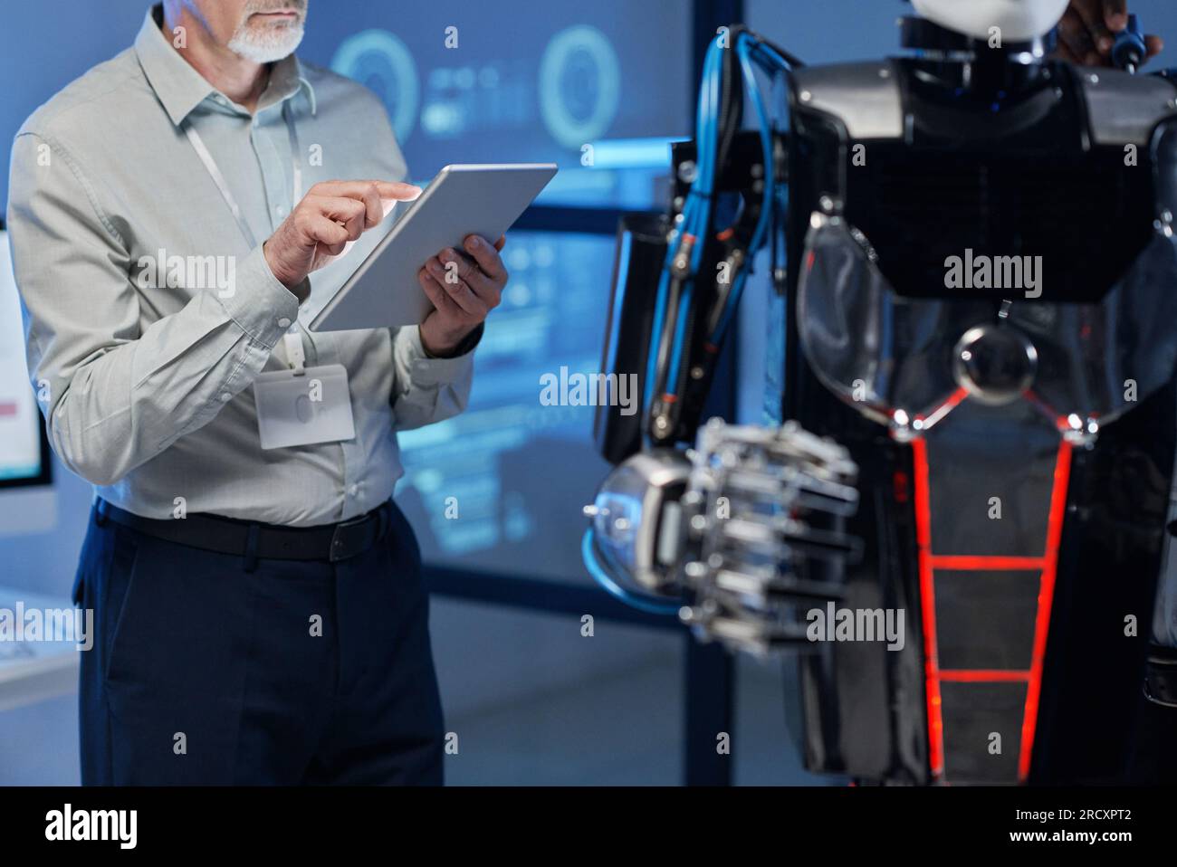 Nahaufnahme eines erfahrenen Ingenieurs, der während seiner Arbeit im Labor ein digitales Tablet verwendet, um sich mit dem Roboter zu verbinden Stockfoto
