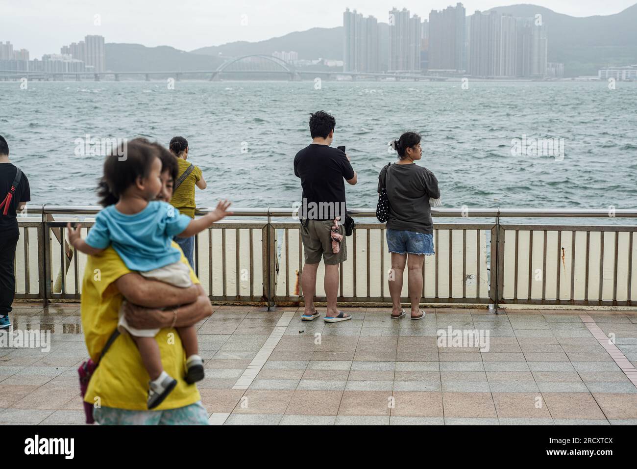 Die Leute wagen sich raus und spüren die Macht des Taifuns Talim in Heng Fa Chuen. In den frühen Stunden des 17. Juli, als sich der Taifun Talim Hongkong nähert, gibt das Hong Kong Observatory um 12:40 Uhr morgens das Warnsignal für den Taifun Nr. 8 aus Dieses Signal ruft in der ganzen Stadt erhebliche Veränderungen hervor, wobei die meisten Busverbindungen zum Stillstand kommen und die Börse als Reaktion auf die unmittelbare Gefahr ihre Türen schließt. Inmitten dieser Vorsichtsmaßnahmen bietet die MTR (Mass Transit Railway) jedoch weiterhin begrenzte U-Bahn-Dienste an, um sicherzustellen, dass Anwohner und Reisende über ein Transportmittel verfügen Stockfoto