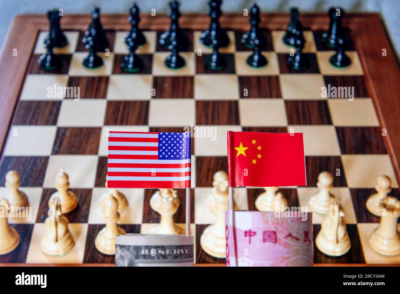 Eine Rolle US-Dollar und chinesischer Yuan mit der Nationalflagge jedes Landes und einem Schachbrett im Hintergrund. Eine globale marktbeherrschende Stellung im Finanzhandel Wettbewerb A Stockfoto