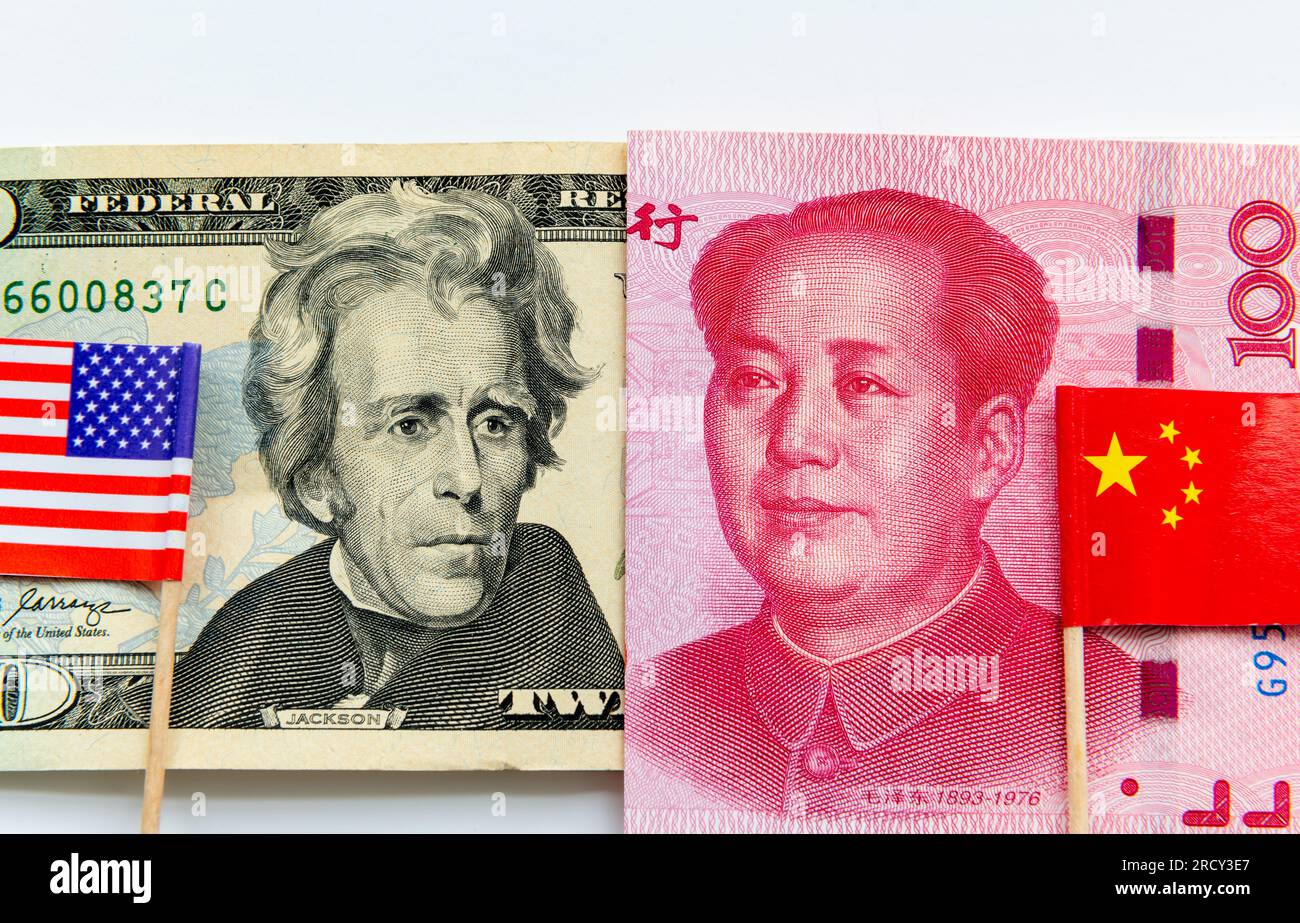 Ein 20-Dollar-Schein und ein chinesischer 100-Yuan-Schein, wobei die US-amerikanischen und chinesischen Nationalflaggen in Weiß isoliert sind. Internationale Finanz- und Handelskonkurrenz CO Stockfoto