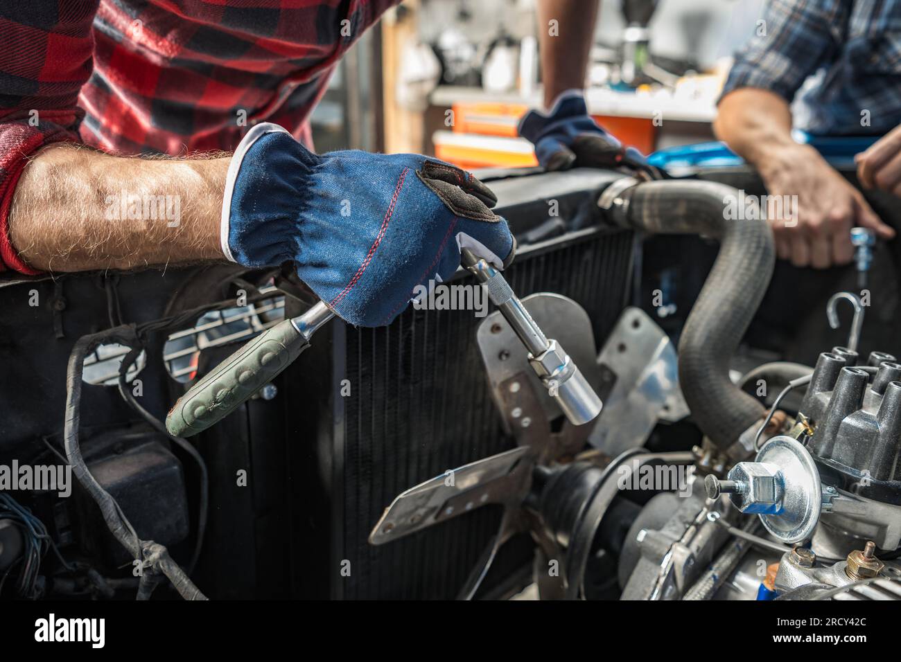 Professioneller, kaukasischer Mechaniker, der sich um den Motor eines klassischen Autos kümmert. Amerikanisches Muscle-Cars-Design. Stockfoto