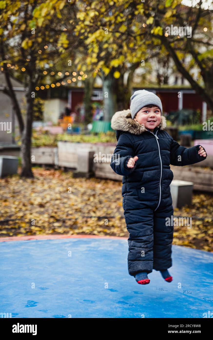 Ein Kind, das auf ein weiches Trampolin springt, fühlt sich auf einer morbiden Oberfläche geschützt. Sicherheits- und Schutzkonzept mit entspanntem Kind, das auf den Türsteher springt Stockfoto