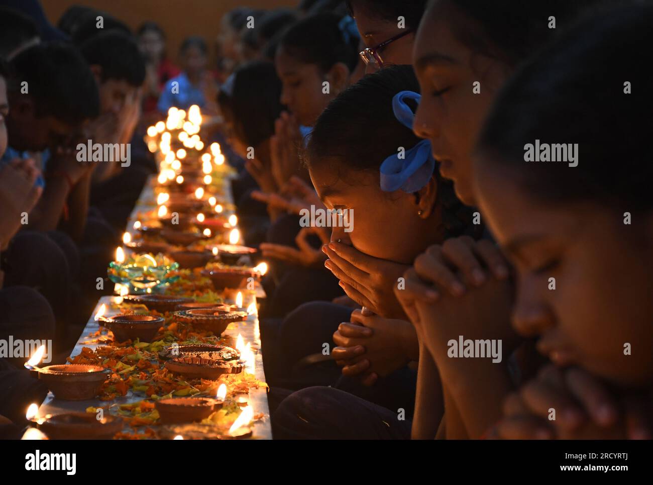 Mumbai, Indien. 17. Juli 2023. Schüler von Shivaji Shikshan Sanstha sitzen in einer Schlange, zünden eine Diya (Erdlattnampe) an und beten anlässlich Ashadha Amavasya in Mumbai mit gefalteten Händen. Deep (Beleuchtung Erdlampen) Pooja wurde mit Lampen unterschiedlicher Größe und Metallen durchgeführt, die alle zusammen beleuchtet wurden. Die Schüler saßen vor den Tieflampen (Erdlampen) und sangen Slokas (sanskrit zitiert), während sie sich auf die Flamme der Erdlampen konzentrierten, die helfen, die Konzentration zu verbessern und positive Vibes, Licht und Energie zu bringen. Kredit: SOPA Images Limited/Alamy Live News Stockfoto