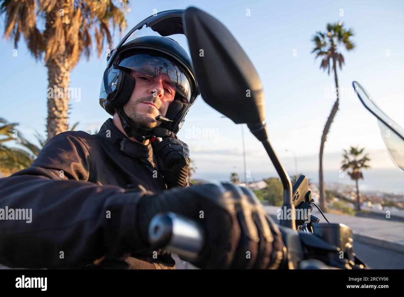 Ein Motorradfahrer setzt seinen Helm auf, bevor er mit seinem Motorrad auf einen Roadtrip geht Stockfoto