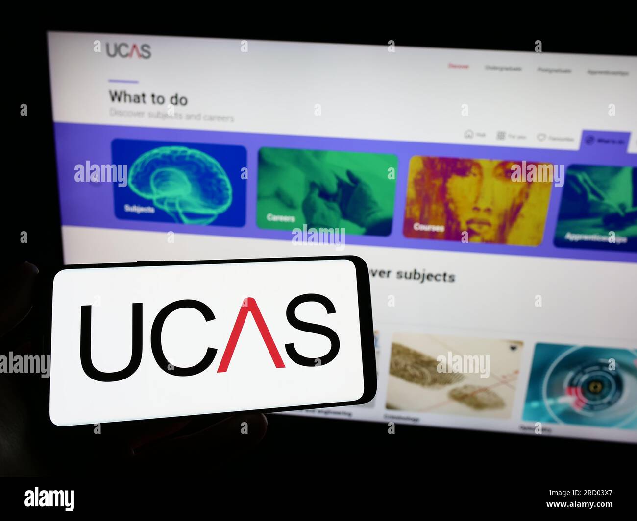 Person, die ein Smartphone mit dem Logo des Universities and Colleges Admissions Service (UCAS) auf dem Bildschirm vor der Website hält. Konzentrieren Sie sich auf das Display des Telefons. Stockfoto