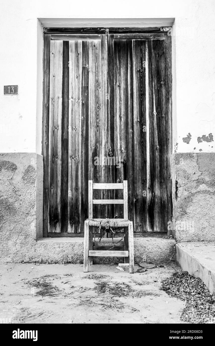 Alte braune Holztür und kaputter Stuhl in Spanien Stockfoto