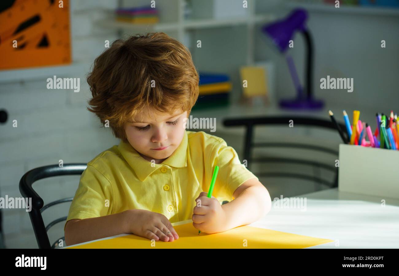 Ein kleiner Schuljunge, der Hausaufgaben macht, sitzt am Schreibtisch. Ein Junge aus der Grundschule. Kleiner Schuljunge mit bunten Bleistiften. Kinder zeichnen. Kreativität Stockfoto