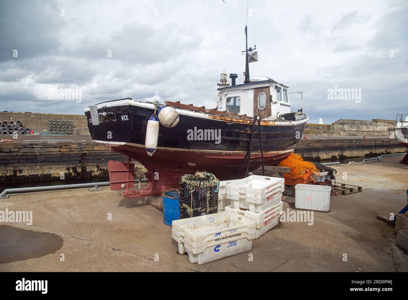 Wick, Caithness, Schottland, Juli 2. 2023, Ein kleines Fischerboot auf dem Trockendock am Hafen. Stockfoto