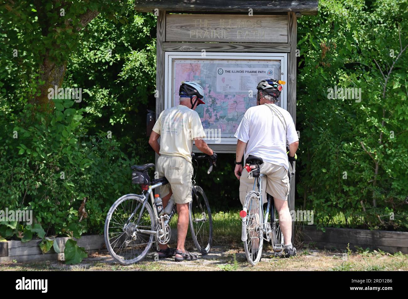 West Chicago, Illinois, USA. Zwei Radfahrer machen Halt, um eine Karte auf dem Illinois Prairie Path Trail im westlichen Vorort von Chicago zu lesen. Stockfoto