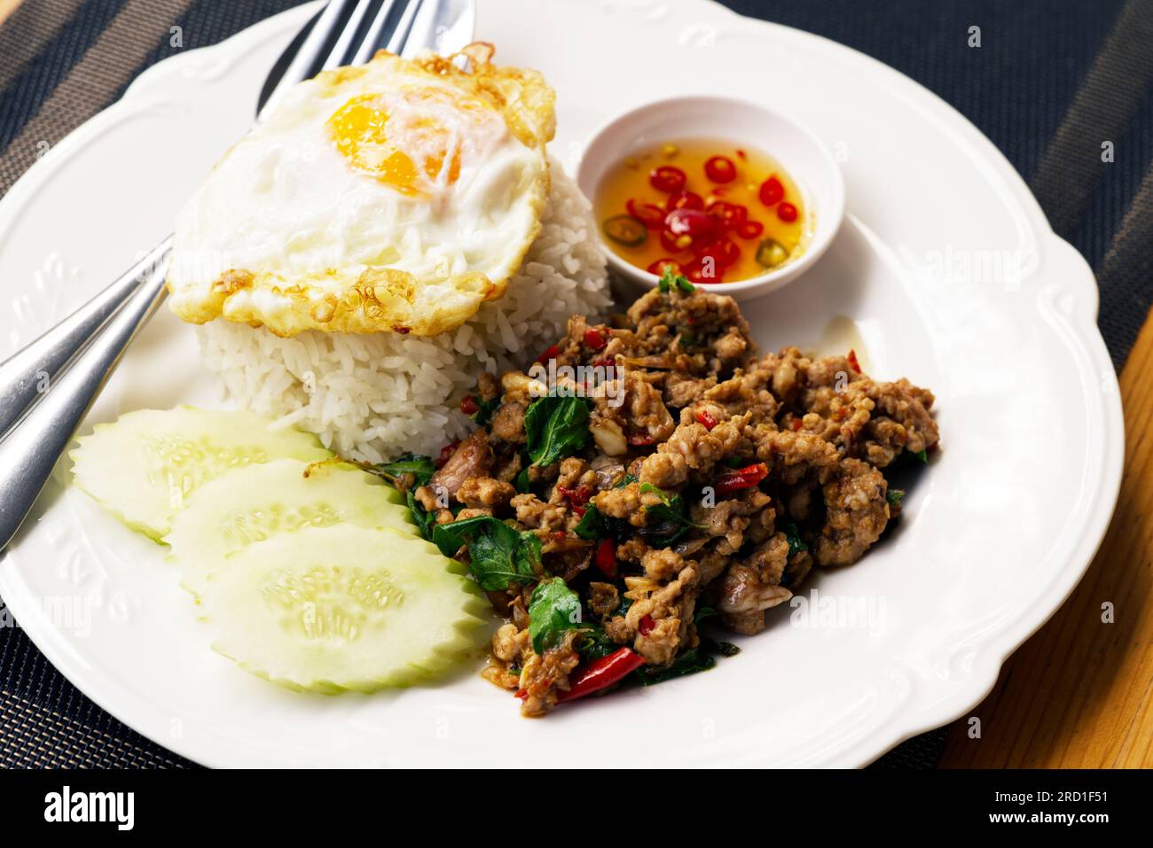 Klassische thailändische Speisen, scharfes Menü, Pad Krakau oder gebratenes Schweinefleisch mit basilikum und Chili, Spiegelei auf weißem Reis. Kleine Schüssel mit Fischsoße und Chili Stockfoto