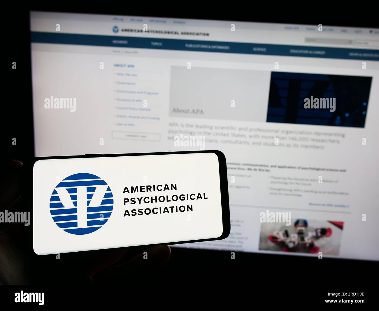 Person, die ein Smartphone mit dem Logo der American Psychological Association (APA) auf dem Bildschirm vor der Website hält. Konzentrieren Sie sich auf das Display des Telefons. Stockfoto