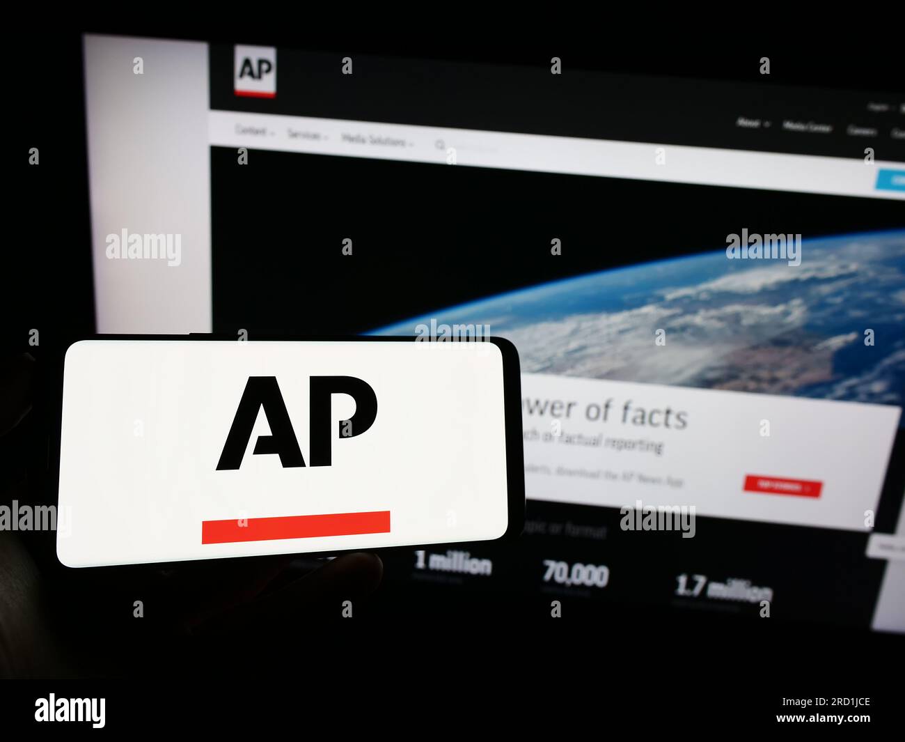 Person, die ein Mobiltelefon mit dem Logo der US-Nachrichtenagentur Associated Press (AP) auf dem Bildschirm vor der Webseite hält. Konzentrieren Sie sich auf das Display des Telefons. Stockfoto