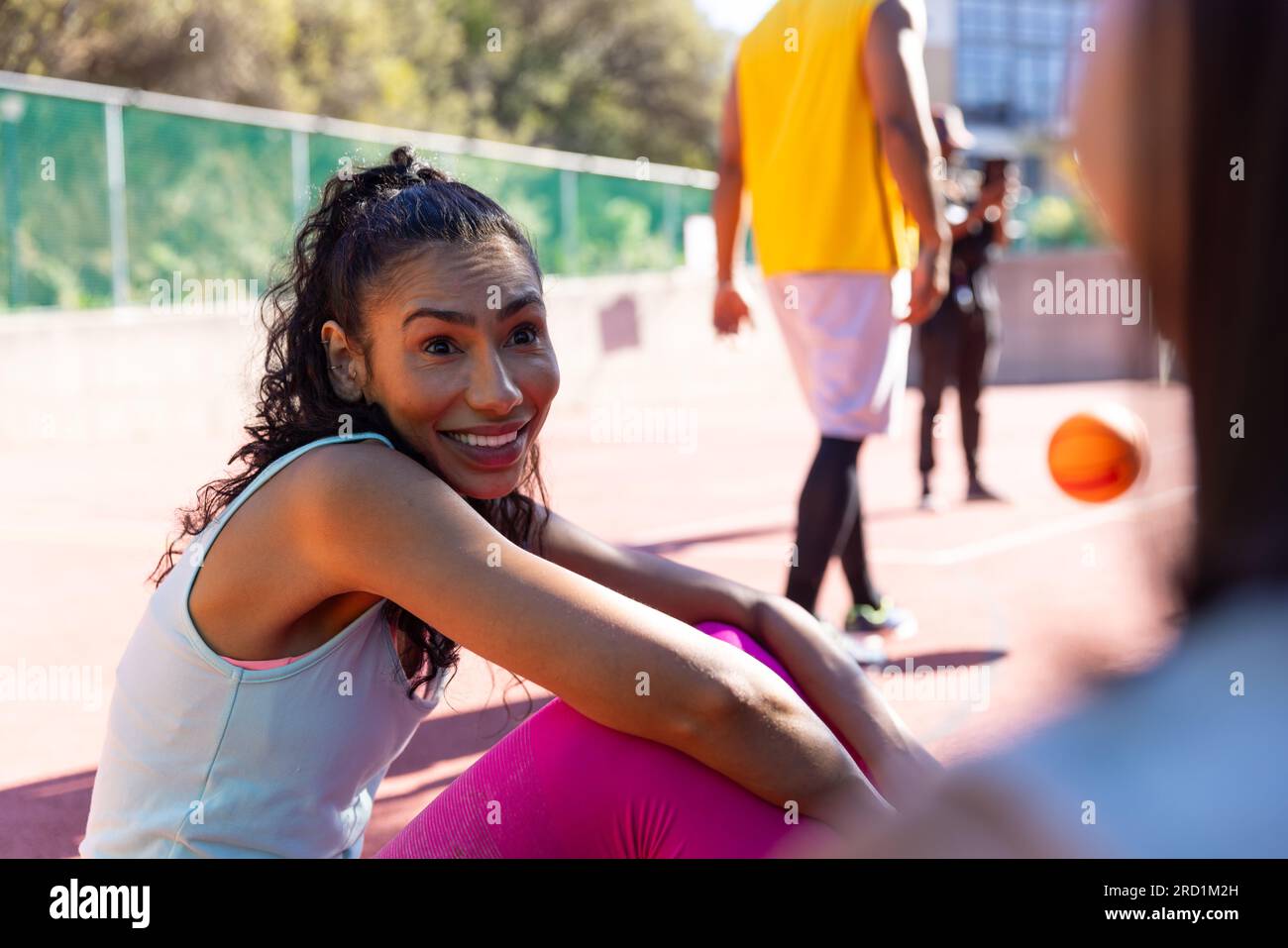Glückliche birassische Freundinnen, die Sportkleidung tragen und sich auf dem Basketballplatz unterhalten Stockfoto