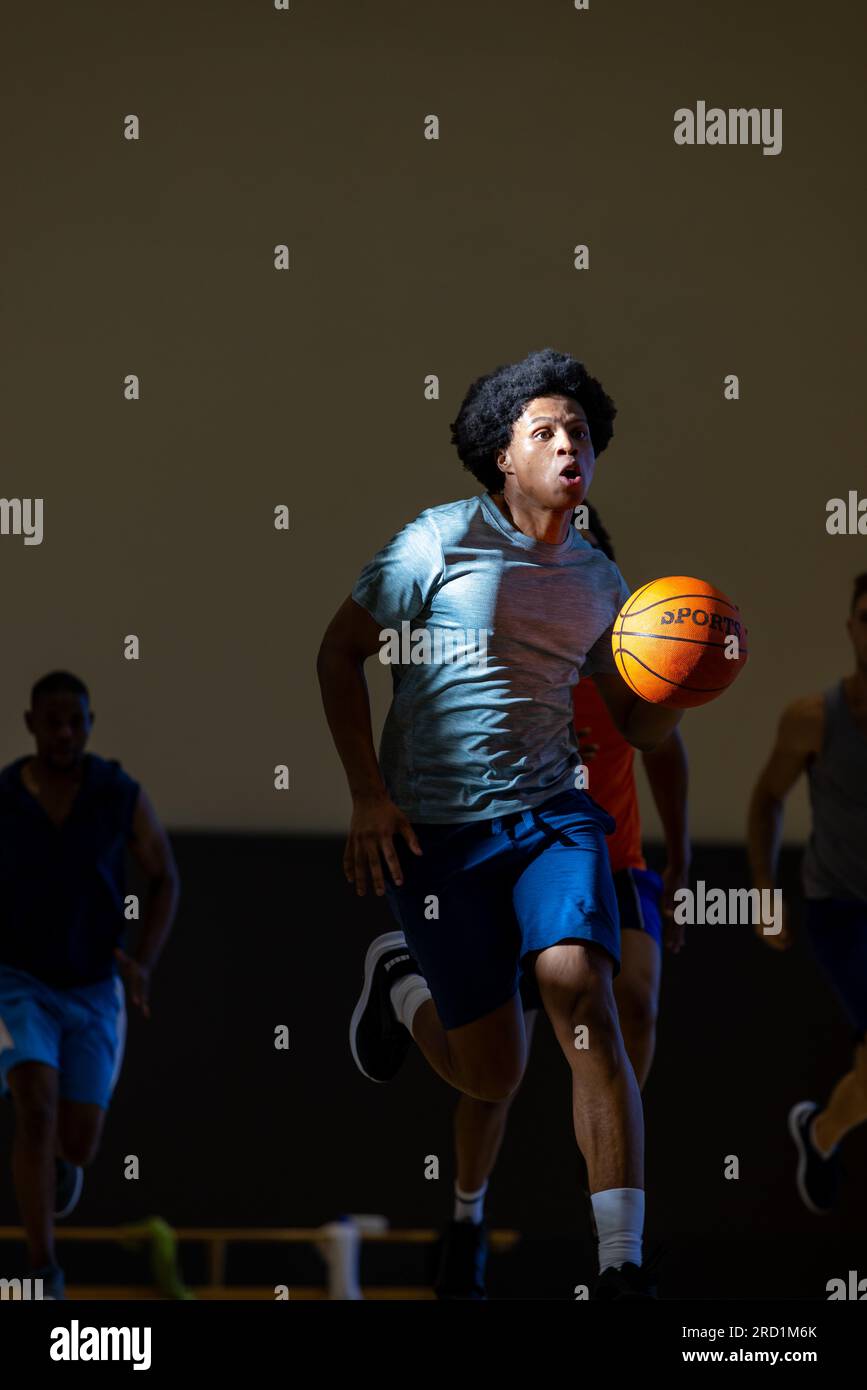 Verschiedene männliche Basketballspieler, die blaue Sportkleidung tragen und im Fitnessstudio Basketball spielen Stockfoto