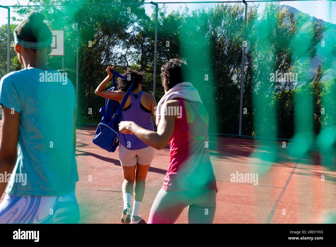 Birassische weibliche Freunde, die Sportkleidung tragen und auf dem Basketballplatz spazieren gehen Stockfoto