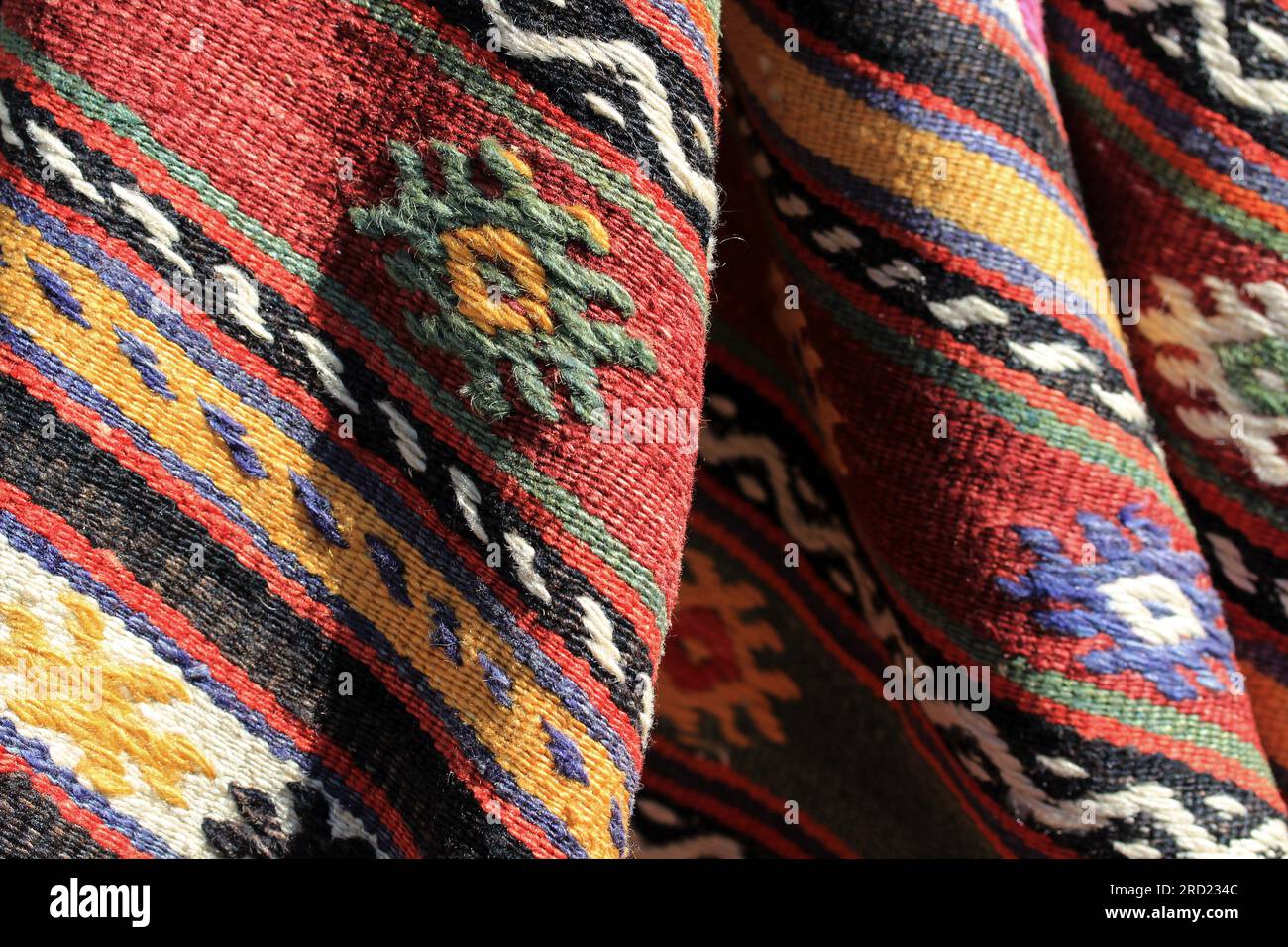 Detail eines traditionellen türkischen Teppichs. Handgewebter Teppich und Teppichmotive. Die Falten des Teppichs und die farbenfrohen Ziergegenstände. Stockfoto