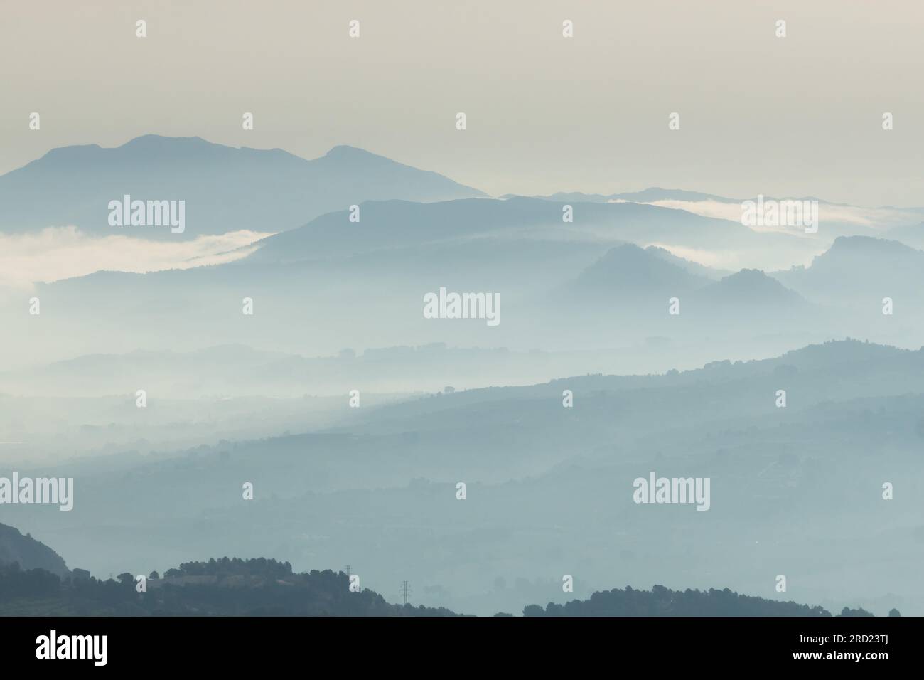 Silhouetten von schichtförmigen Bergen, die von einem Nebel aus dem Alten de les Pedreres in Alcoy, Spanien, umgeben sind Stockfoto