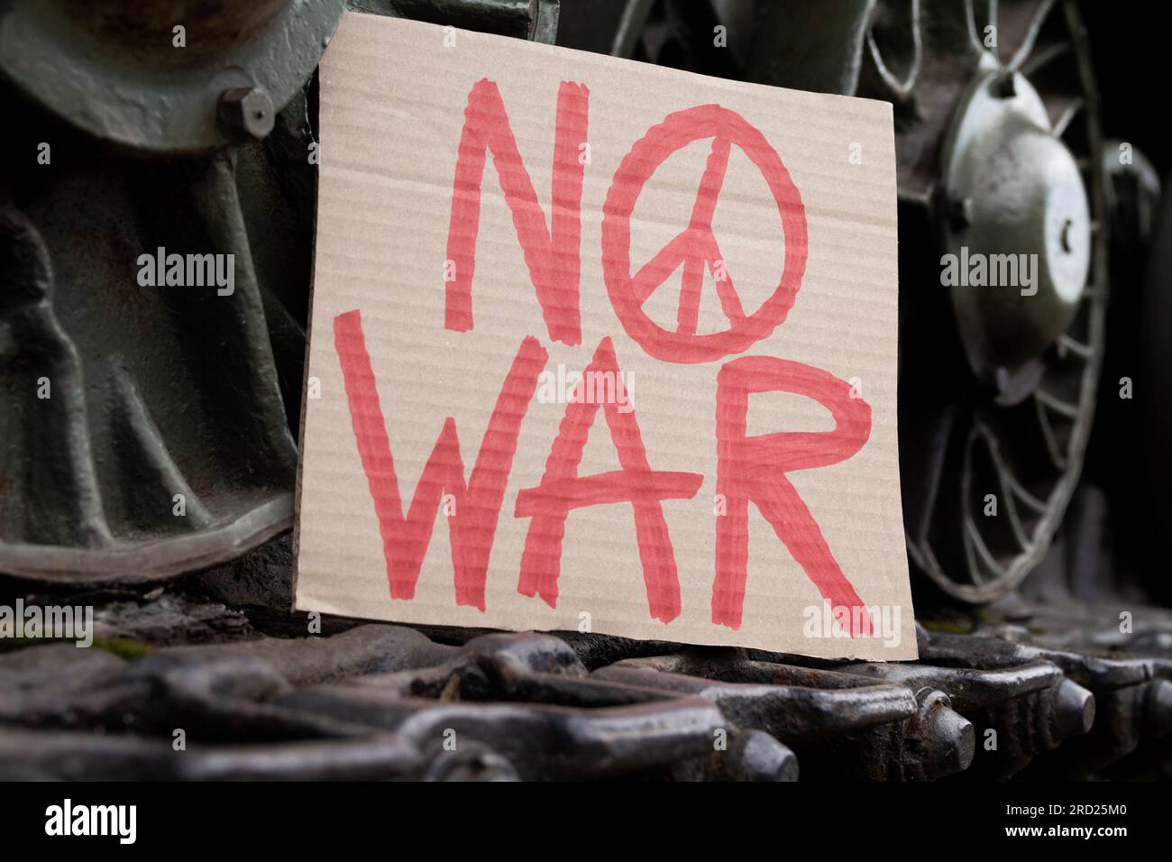 Kein Kriegsschild mit Friedenszeichen auf Raupenketten-Laufrädern. Militärisches gepanzertes Kampffahrzeug mit Anti-Kriegs-Banner. Stockfoto