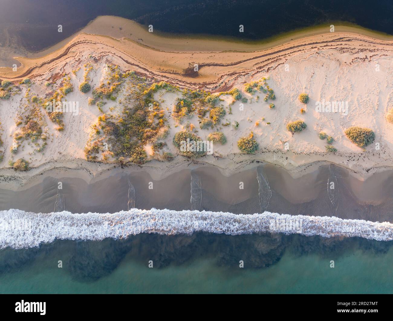 Aus der Vogelperspektive sehen Sie die Wellen, die sich an einem Strand einer schmalen Sandbar auf Swan Island in Queenscliff in Victoria, Australien, tummeln Stockfoto
