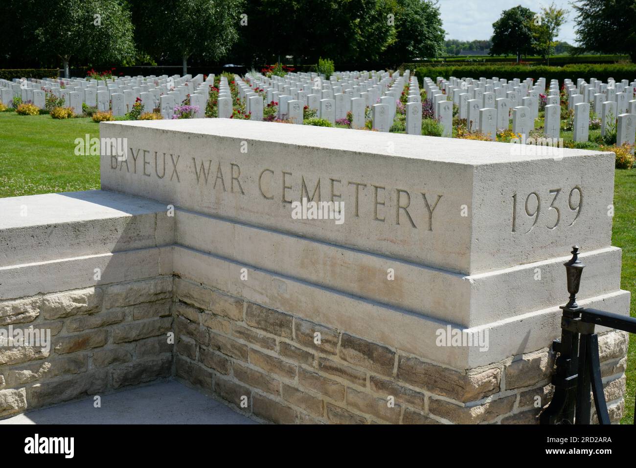 Der Eingang zum Bayeux Kriegsfriedhof mit Reihen von Grabmarkierungen dahinter. Bayeux, Frankreich. Stockfoto