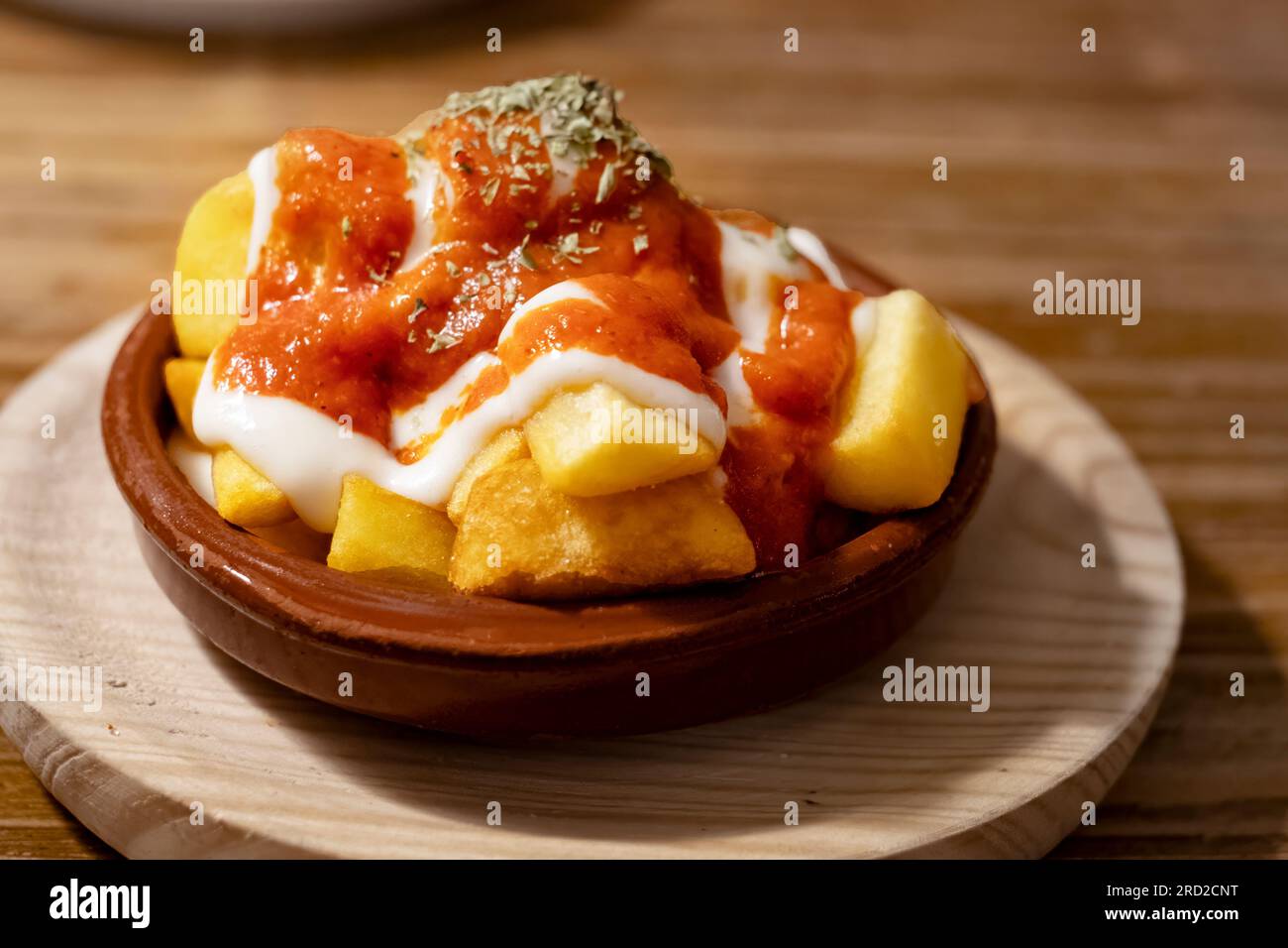 Eine einzelne Tapas-Portion Kartoffel-Bravas oder kleine Kartoffelchips, serviert in einer Schüssel mit Tomatensauce und Mayonnaise-Dressing in einer Tapas-Bar. Stockfoto