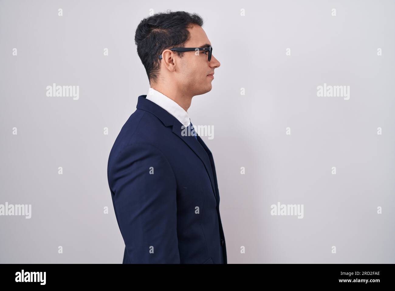 Junger lateinamerikanischer Mann mit Anzug und Krawatte, der zur Seite schaut, entspannte Körperhaltung mit natürlichem Gesicht und selbstbewusstem Lächeln. Stockfoto